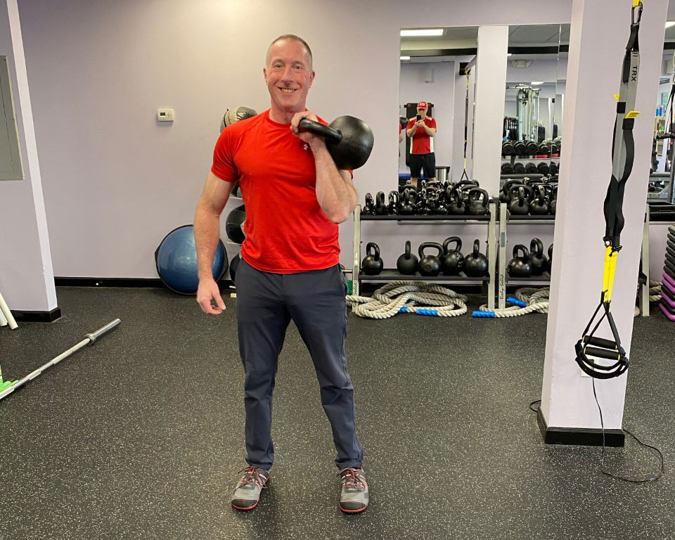 Brian McMaster holding a kettlebell in the rack position in his kettlebell training gym
